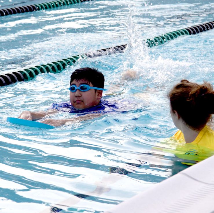 Adaptive swim program swimmer and coach with float board